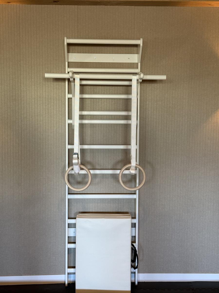 Houten rek met turnringen en een stang aan de wand